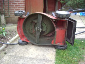 A typical rotary lawnmower on its side showing the blade.